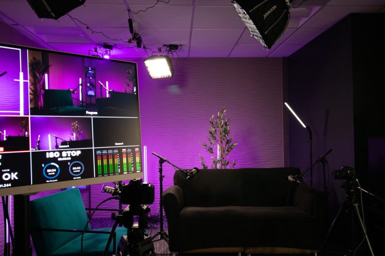 A podcast production monitor showing the studio set